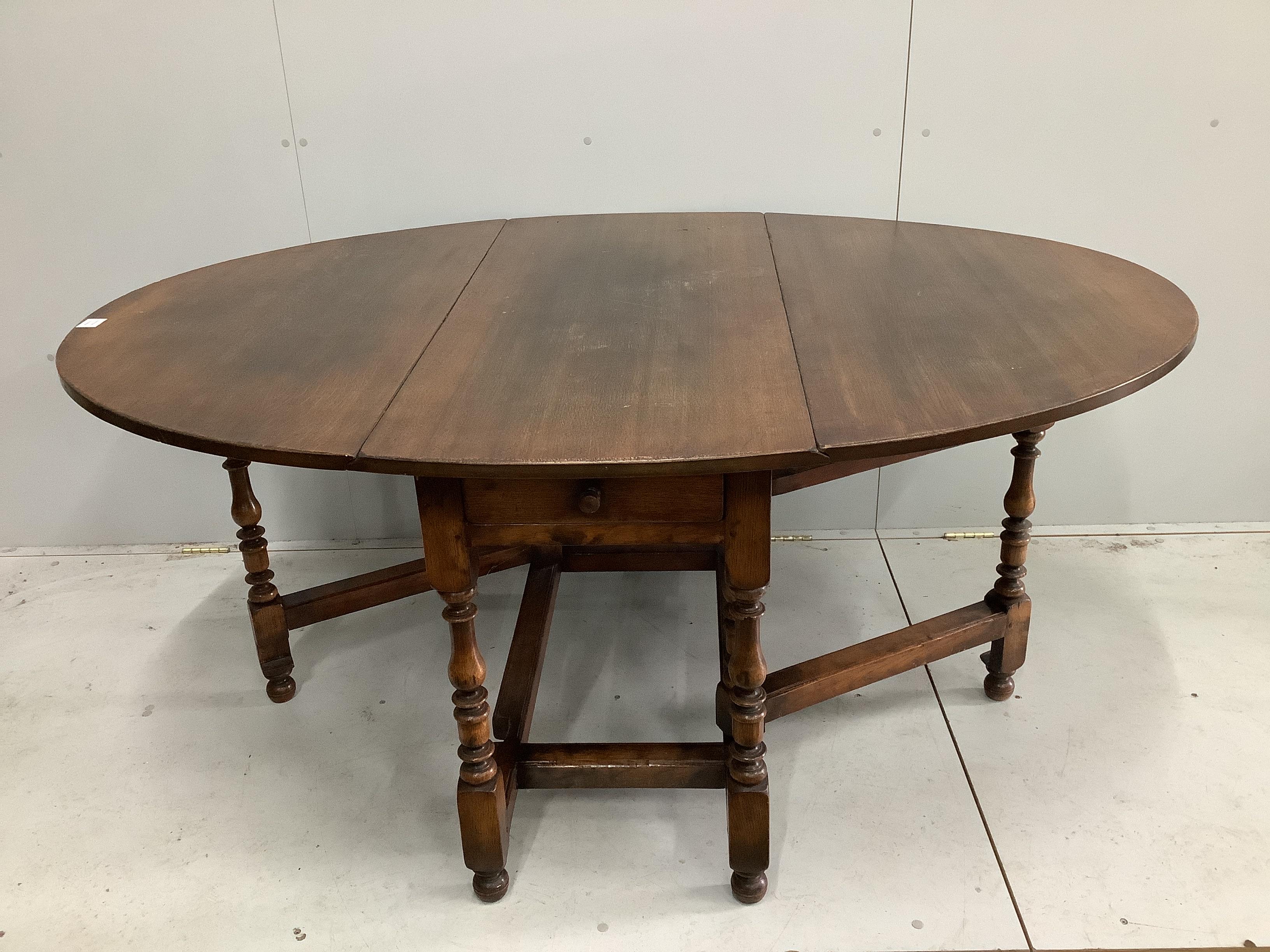 An 18th century style oak gateleg dining table, 170cm extended, depth 122cm, height 75cm together with a set of six oak ladderback dining chairs (one with arms)